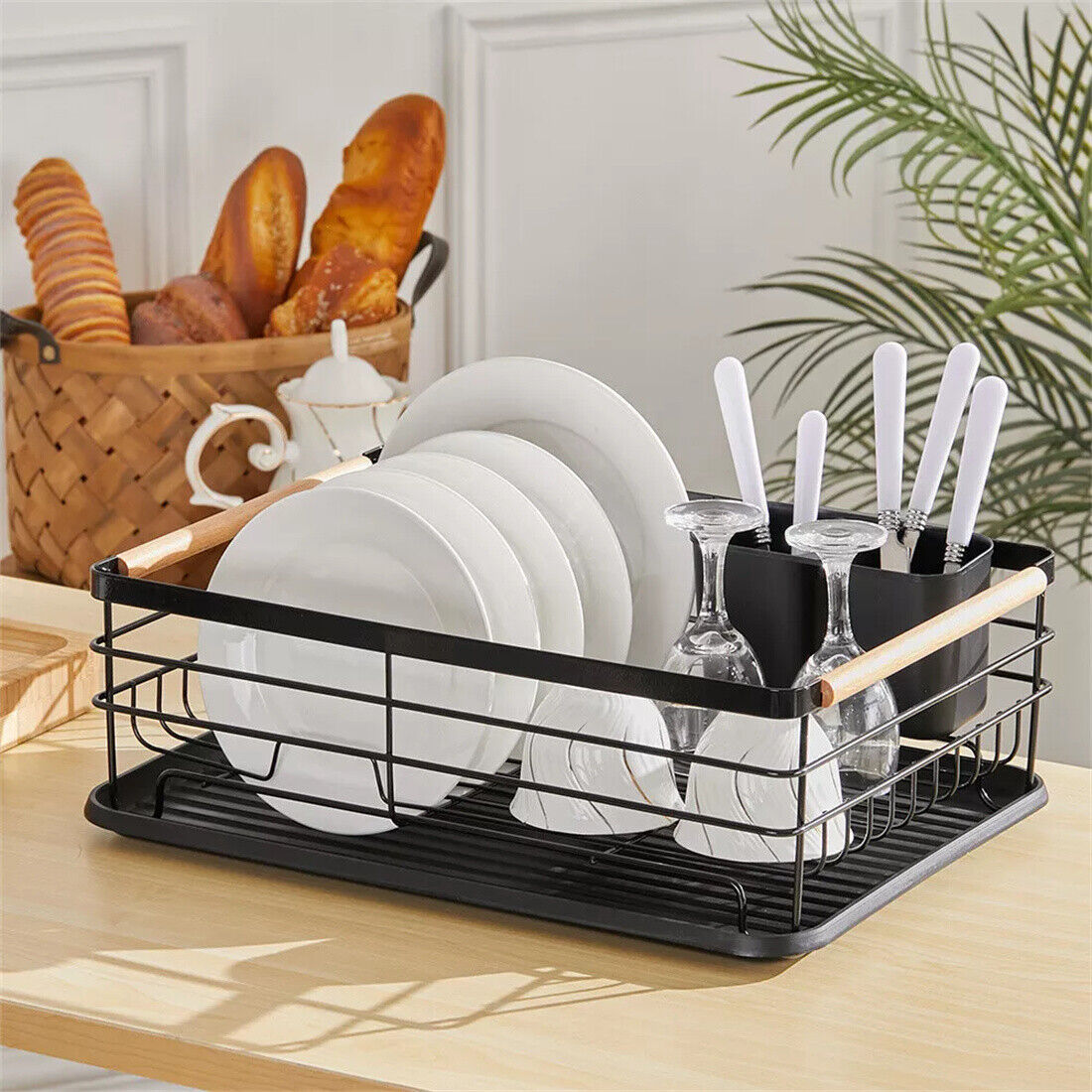 Black dish drying rack with plates, glasses, and cutlery on a kitchen counter.